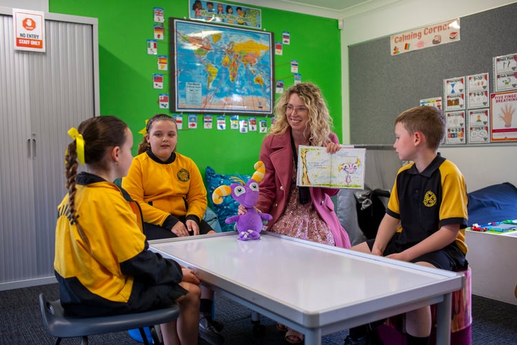 teacher with 3 students reading a book