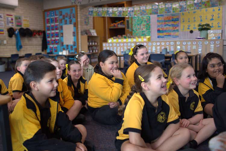 class of students seated on the floor listening to story